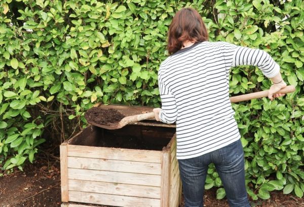 woman with shovel at outside compost bin