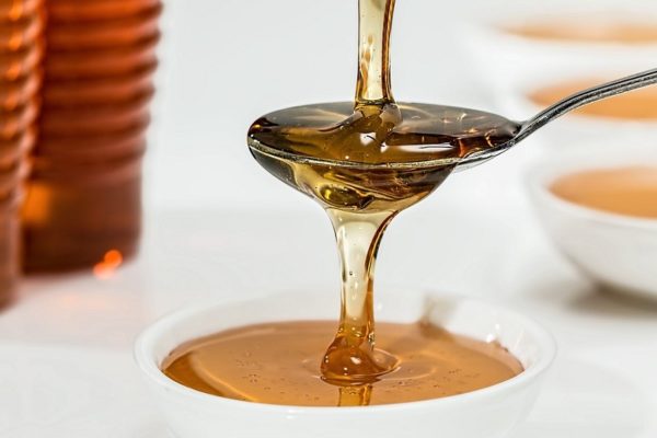 honey overflowing from a spoon into a bowl