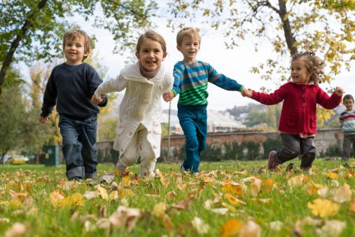 children holding hands and running in field