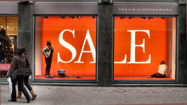 Women walking past sale sign in window