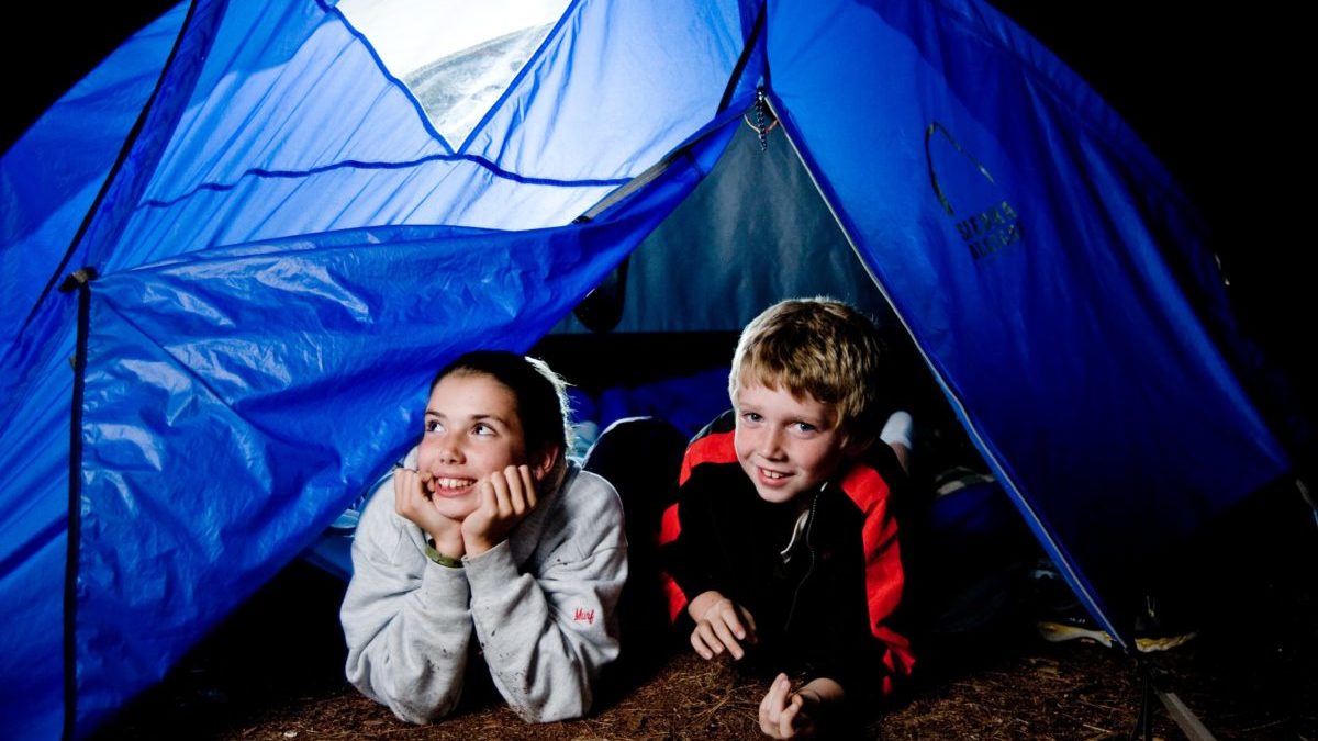 boy and girl looking out from a tent at night