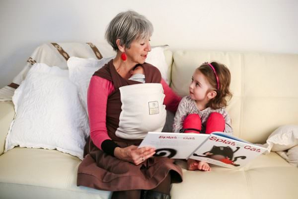 Grandmother reads while babywearing in an Organic Hugabub Wrap