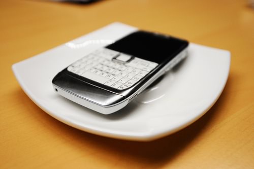 Old smartphone on white plate, with focus on the corner buttons