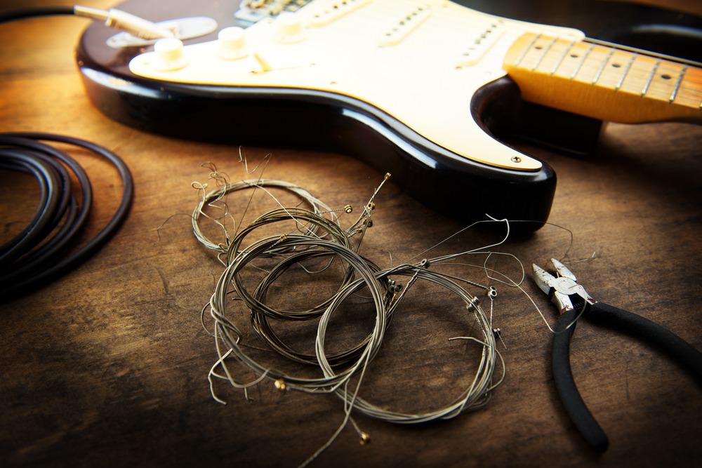 Guitar maintenance. Rolled old guitar strings and an electric guitar. Changing guitar strings.