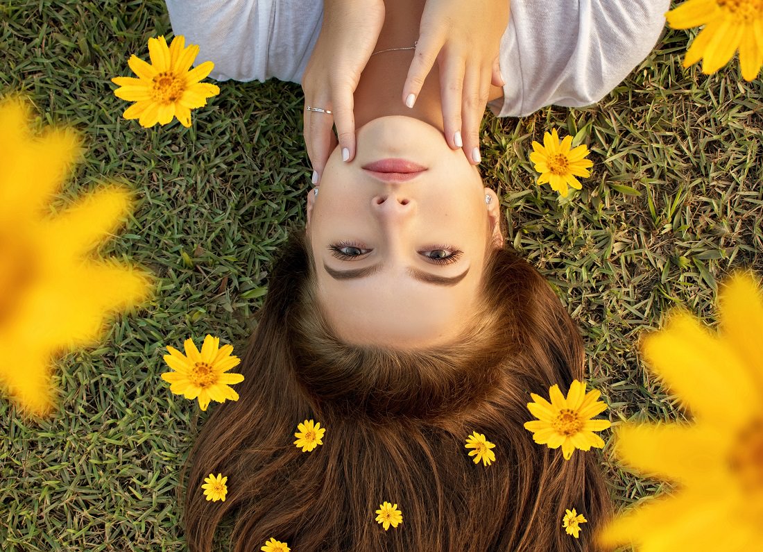 woman lying on grass, surrounded by yellow flowers