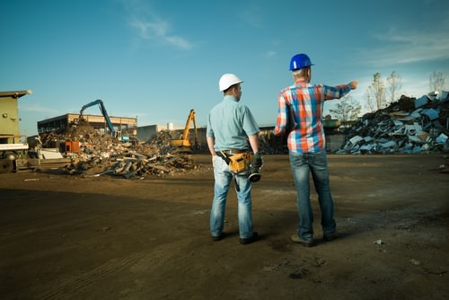 2 workers looking at construction waste