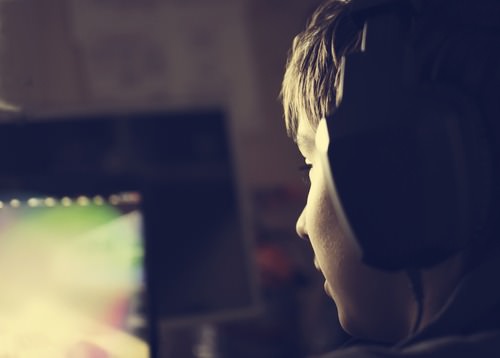 young boy with headphones playing video game
