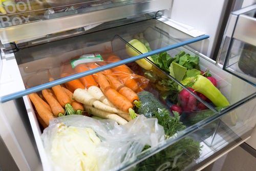 Open fridge filled with vegetables - Tips to reduce food waste 