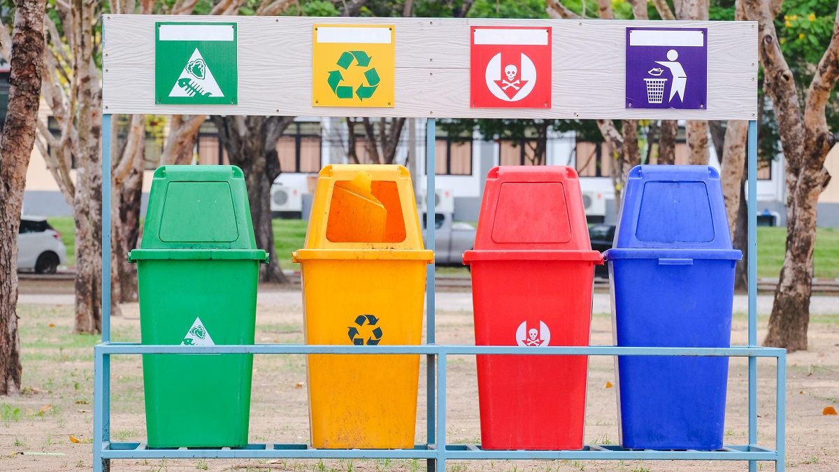 A row of recycling and garbage bins at a public park