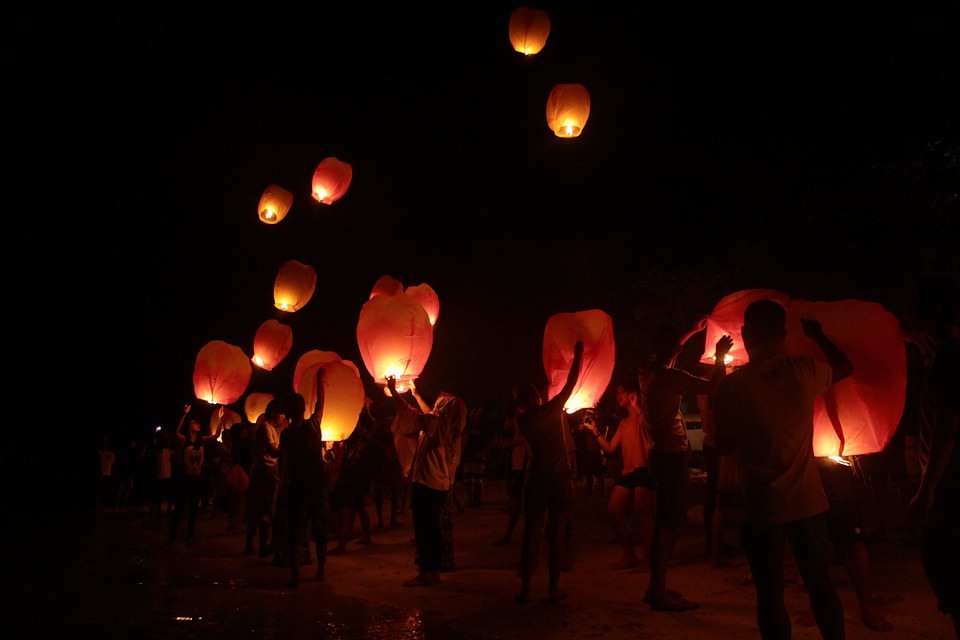 people releasing lanterns into the night sky
