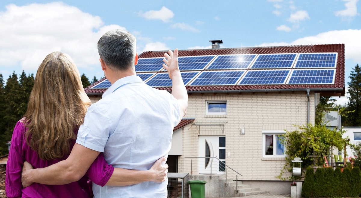 couple standing front of their house with solar panels