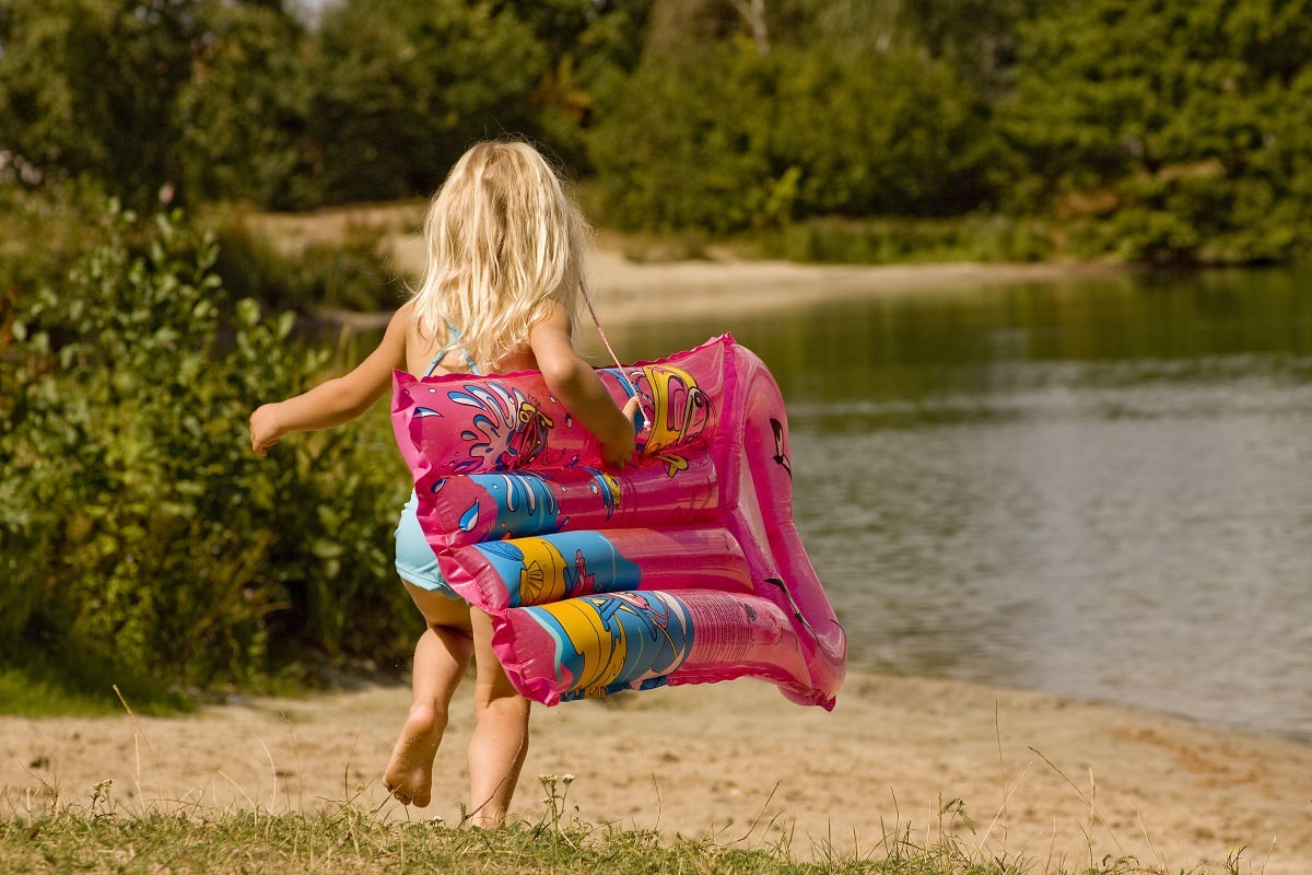 girl running towards lake with air mattress