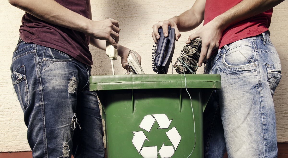 Two men putting electronic waste into recycle bin