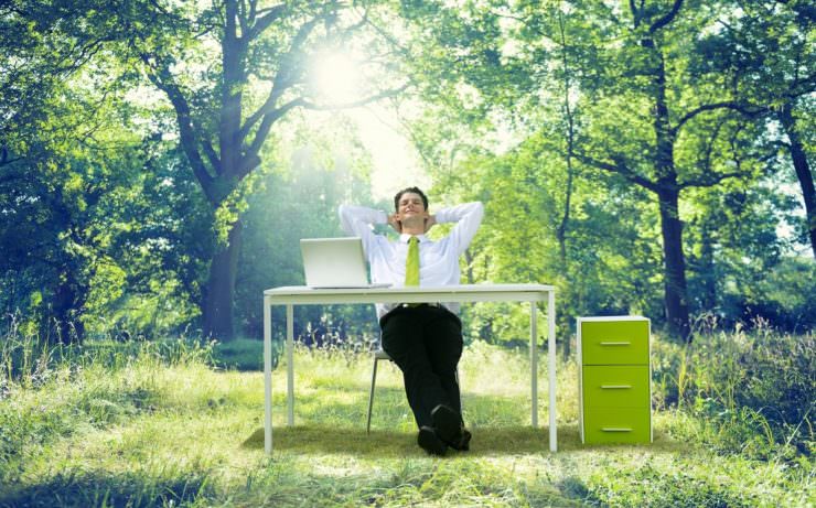 man relaxing at desk in green outside environment