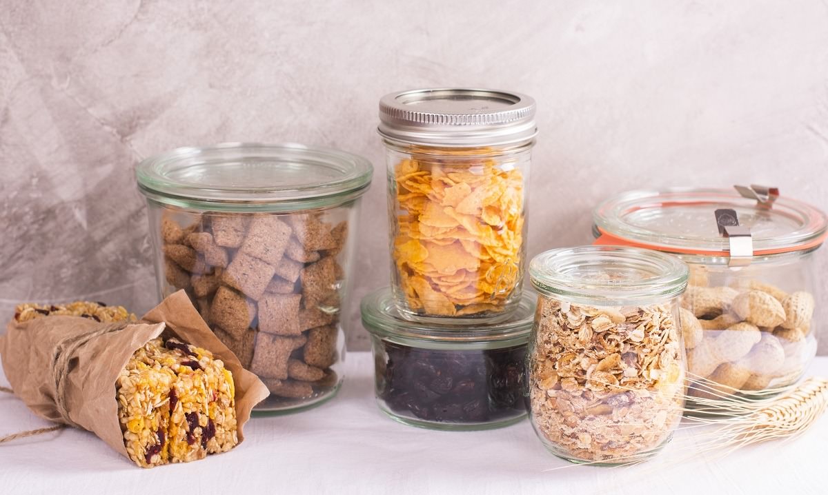 Cereals, nuts, and fruit in glass jars and snack bar wrapped in wax paper