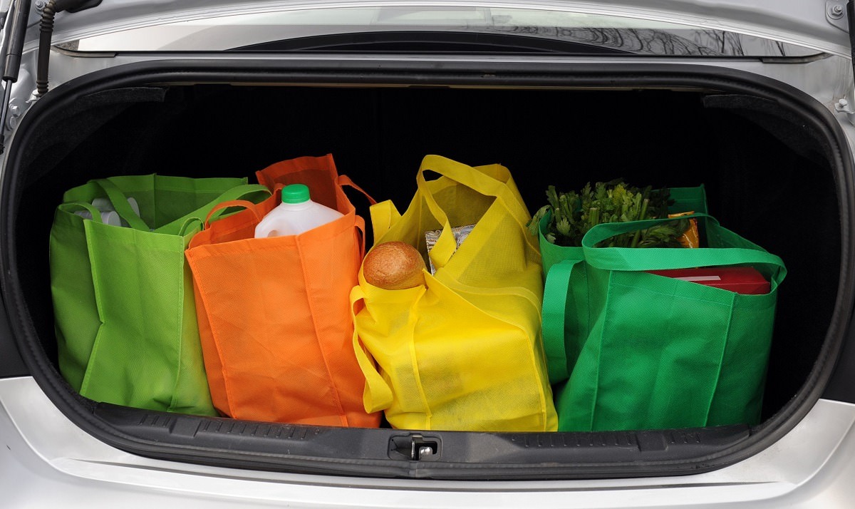 Four colorful shopping bags filled with groceries in the trunk of a car