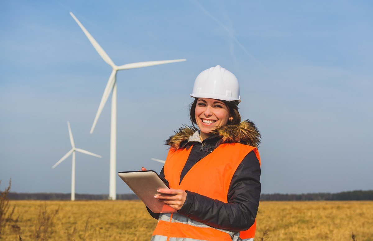 woman engineer with tablet in front of wind turbines