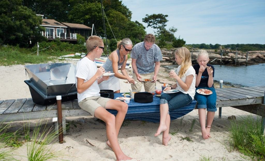 family picnicking on beach with solar oven