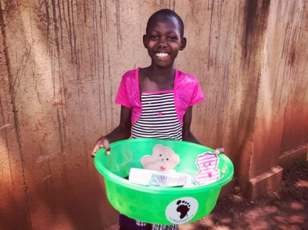 young girl holding a tub filled with basic medical supplies