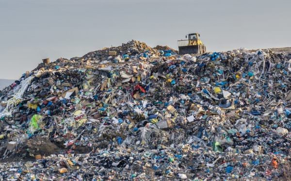bulldozer on pile of garbage in landfill