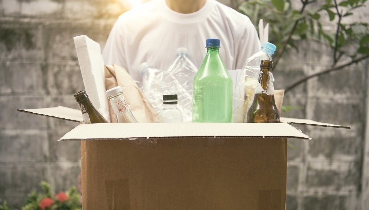 man holding cardboard box with items to recycle