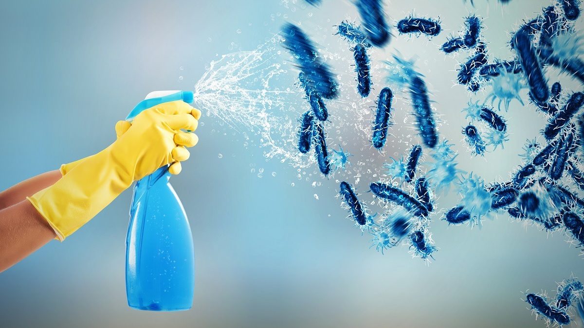 hands in rubber gloves spraying bottled cleaner at germs