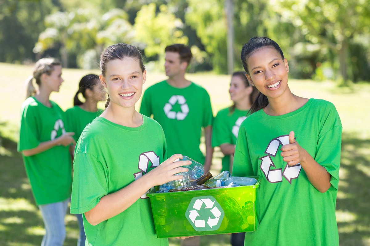 group of youth wearing T-shirts with recycling logo and holding recycling bin