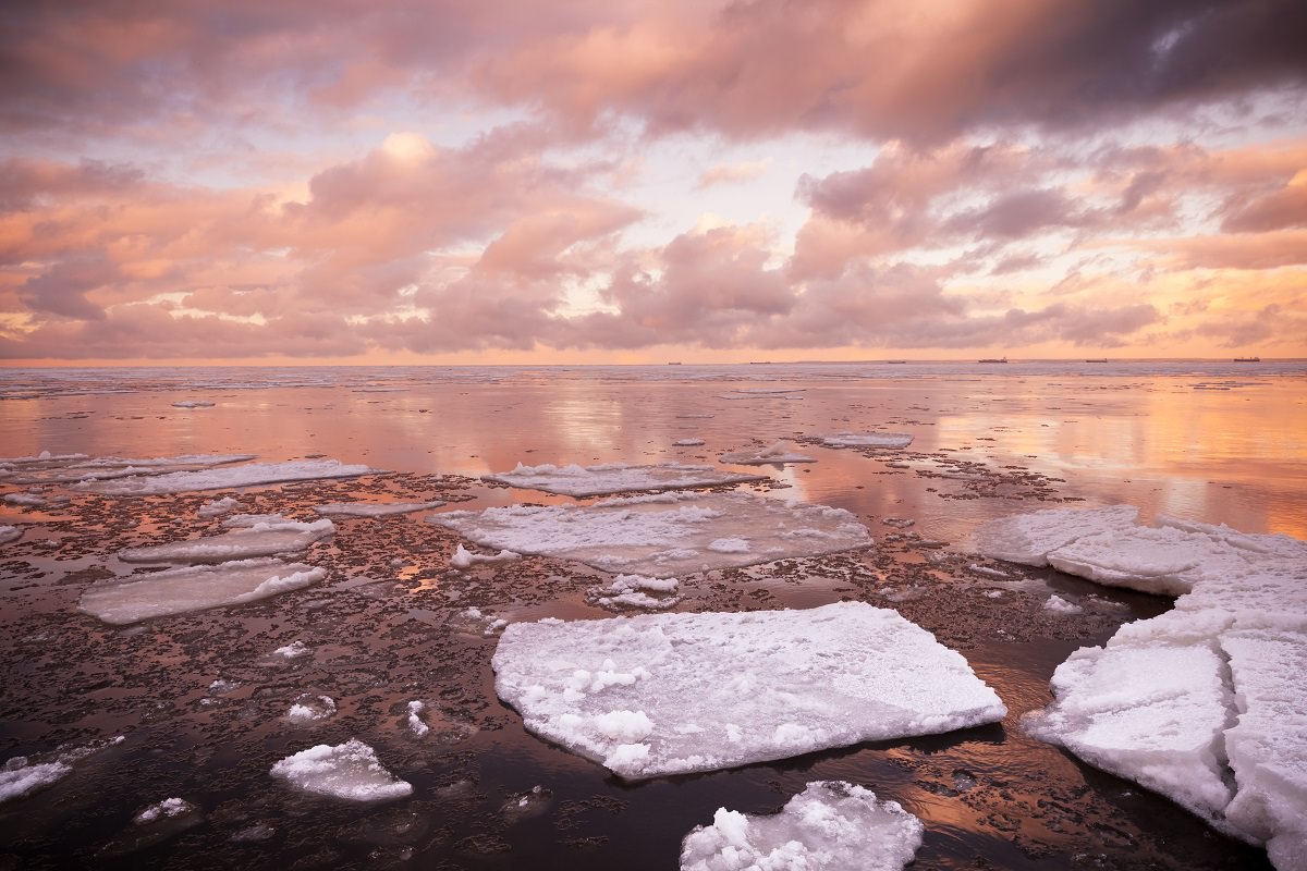 setting sun over ocean with melting ice fragments