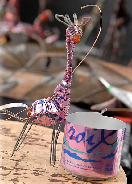 pink giraffe being created from discarded beverage can