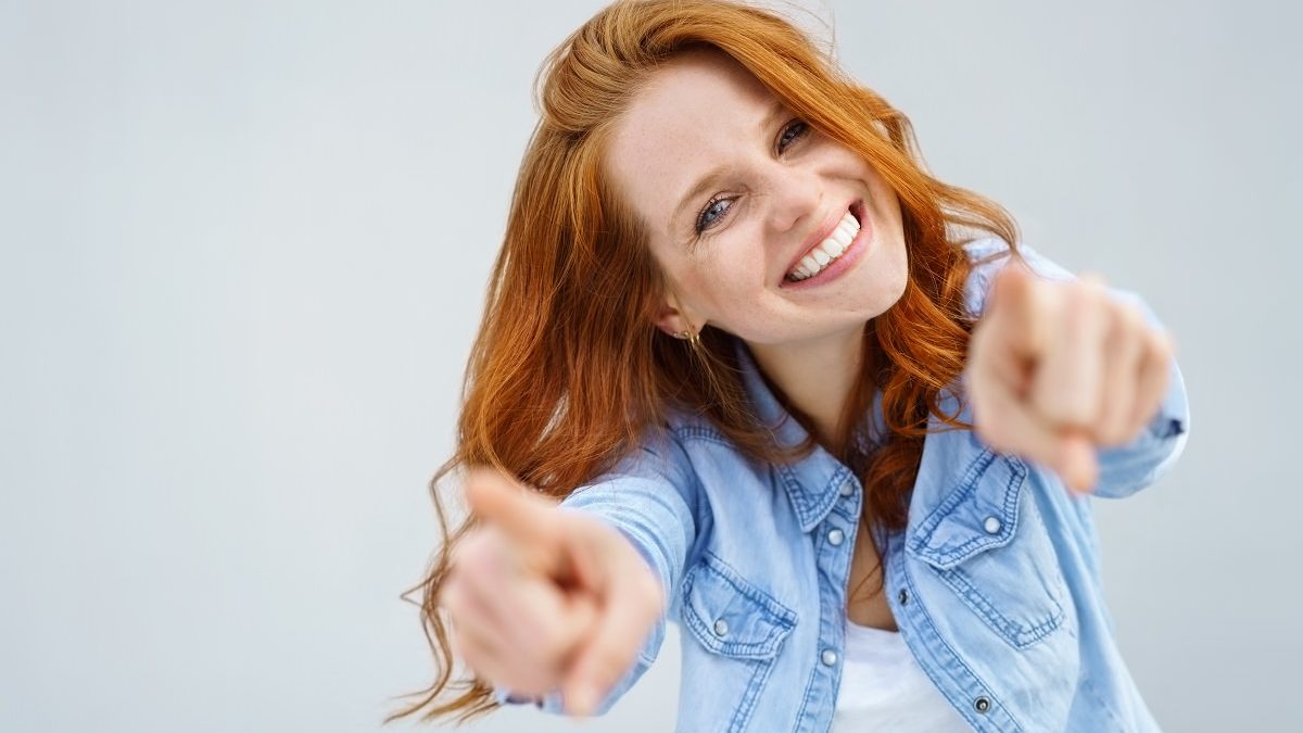 smiling young woman pointing towards viewer