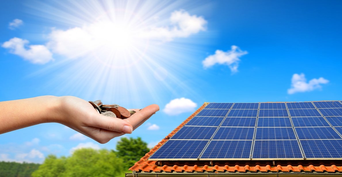 Solar panel on the roof of the house and coins in hand