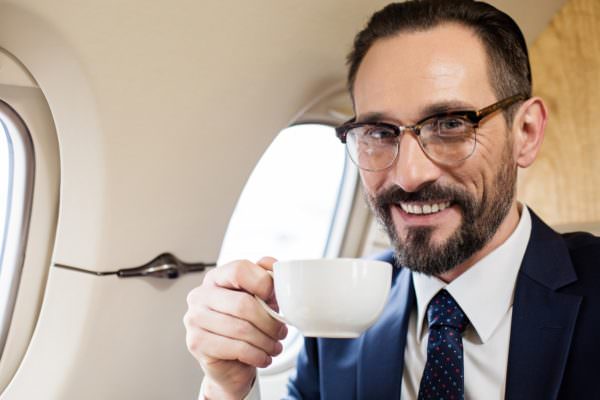 man holding coffee cup on airplane and smiling