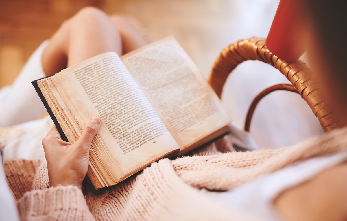 women in sweater with an old book in her lap