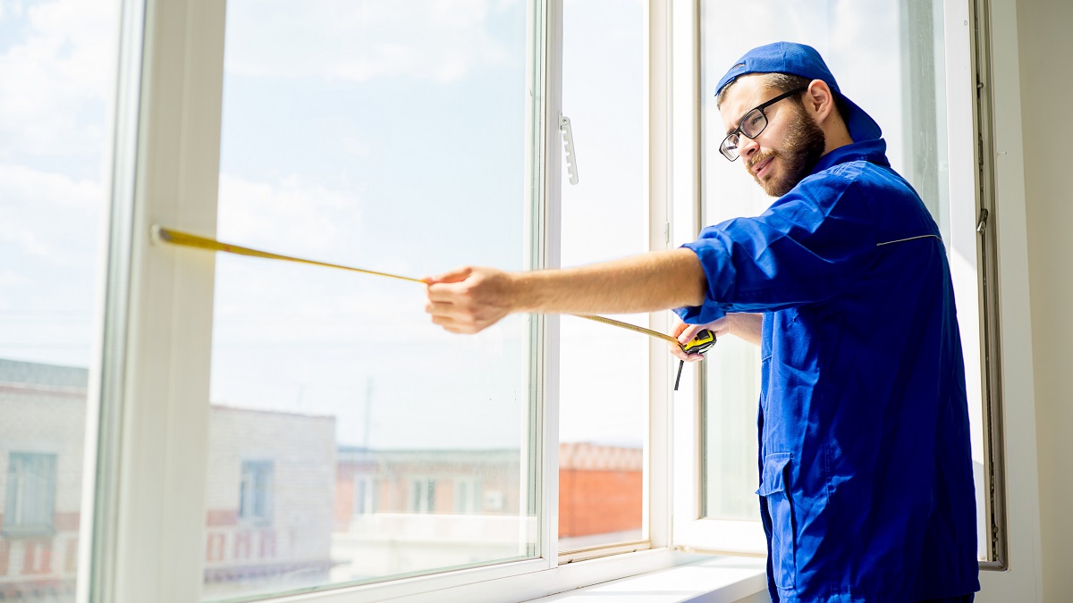 Window installation worker measuring window
