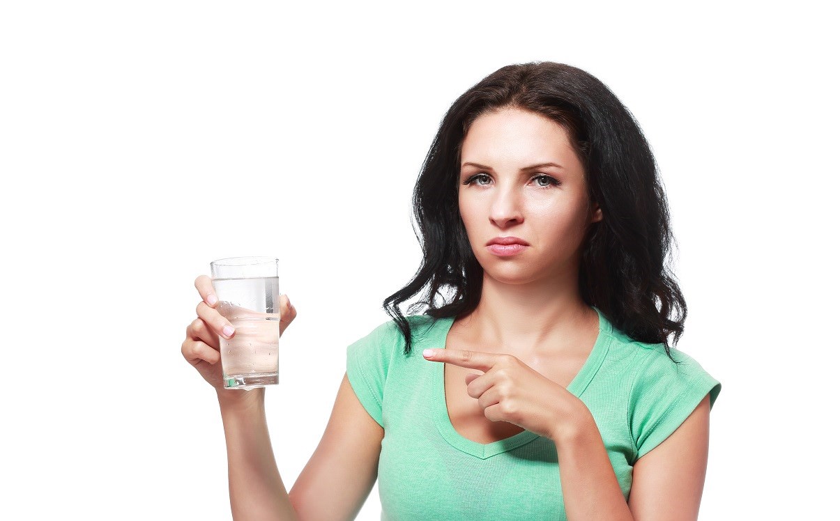 young woman looking unhappy with glass of water