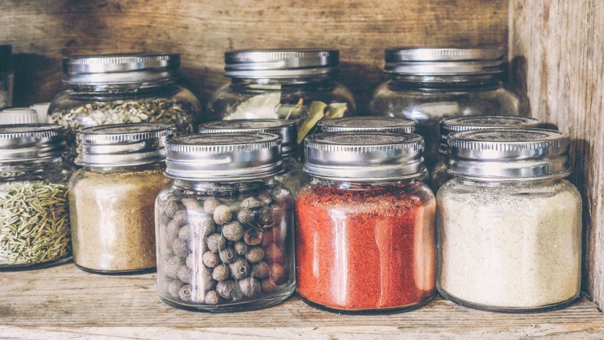 spices and herbs in glass jars on shelf