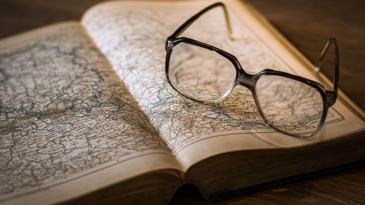 glasses on old book, open to pages showing map