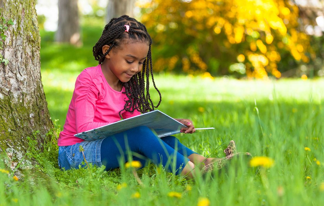 young girl setting outside reading a book