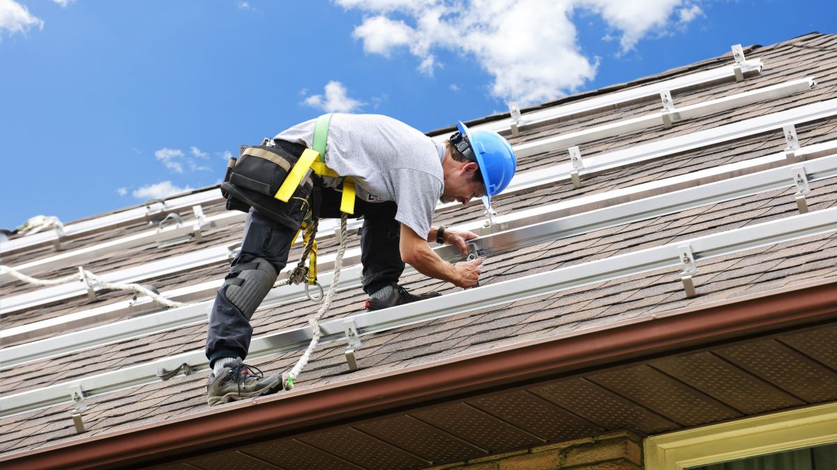 Worker installing rails on roof for solar panels