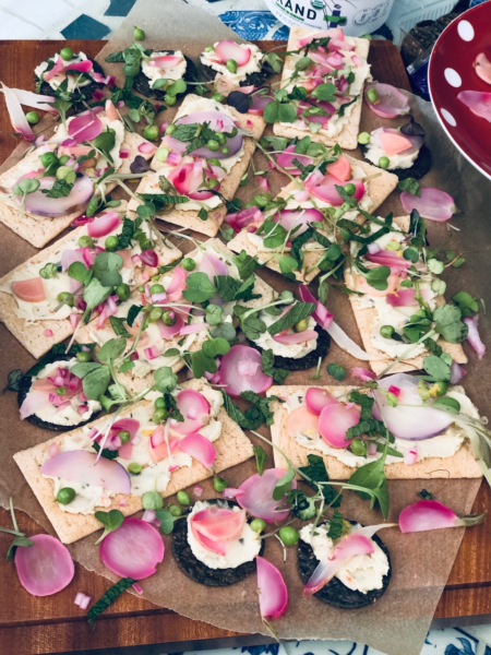 crackers topped with radishes, greens, plant-based cheese, and marinated red onions