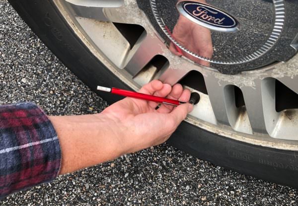 close-up of man's hand checking tire pressure