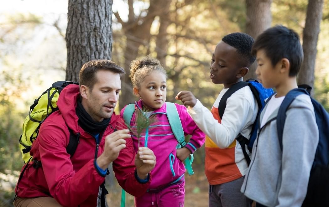 teacher and kids in woods examining plant