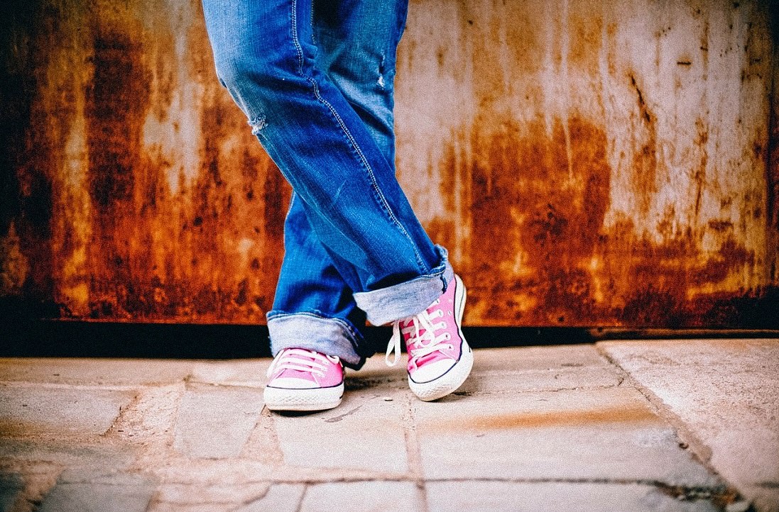 legs of person wearing blue jeans and sneakers