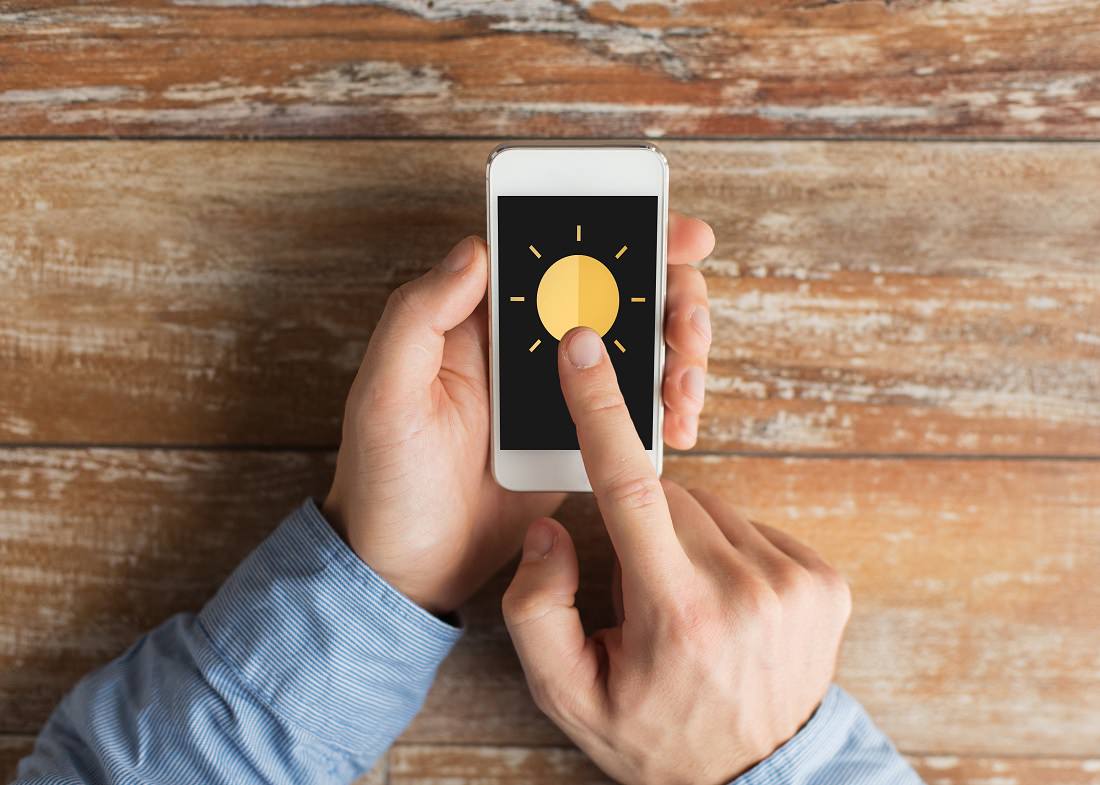 man's hands holding smart phone with sun icon