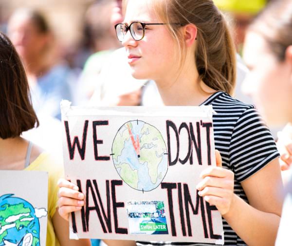 young woman holding sign at climate change protest