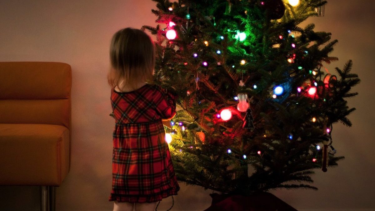 little girl stands in front of Christmas tree