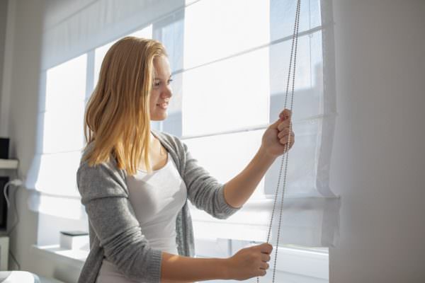 woman lowering window blinds