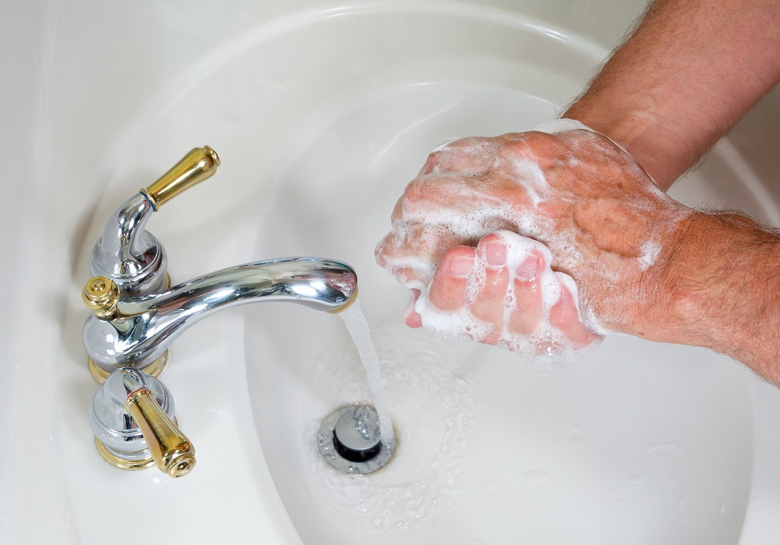 close-up of man's soapy hands over sink with running water