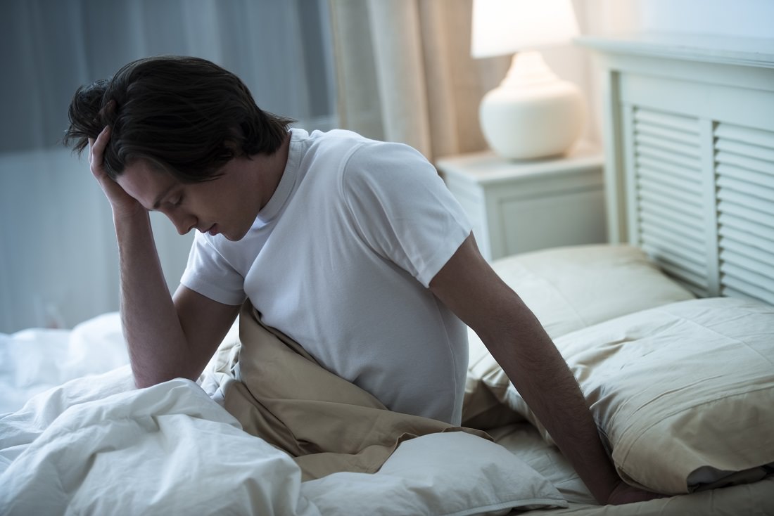 man suffering heading in bed