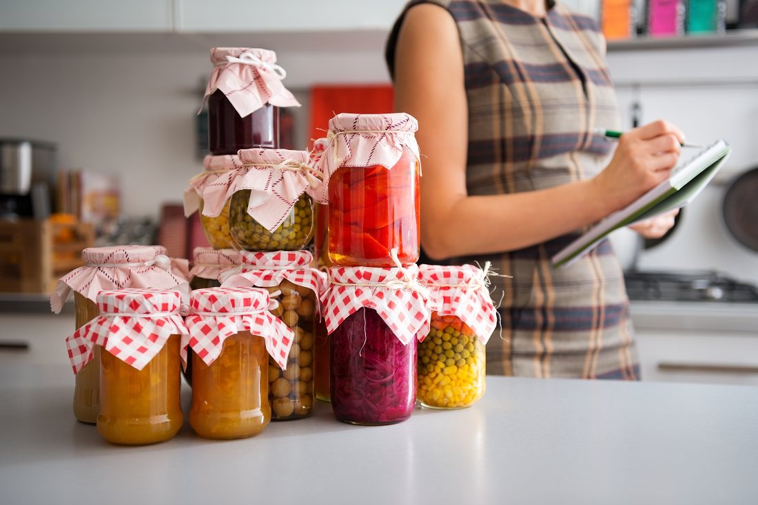food preserved in jars, woman checking off list in background